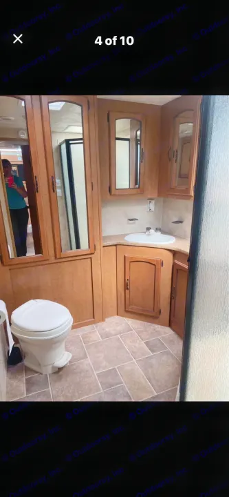 Well-maintained RV rental bathroom showing toilet, corner sink, mirrored cabinets, and a peek of the shower.. Puma Puma 2011