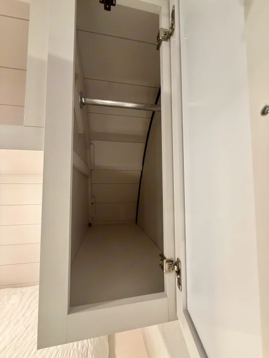 Open white RV rental closet with a hanging rod. Shiplap interior offers compact wardrobe storage for your trip.. Jayco SLX 175BH 2026
