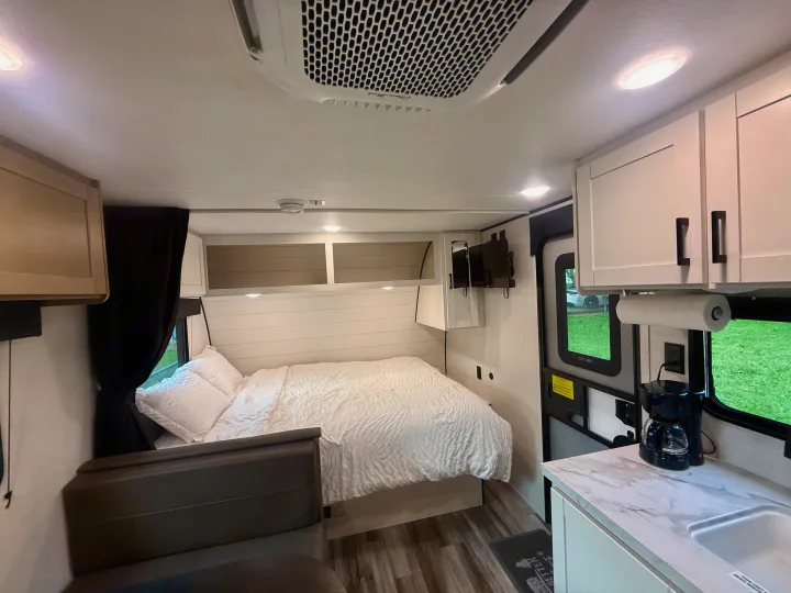 Inside a cozy RV rental: bedroom with a queen bed, integrated kitchen, and overhead AC unit, providing comfort.. Jayco SLX 175BH 2026