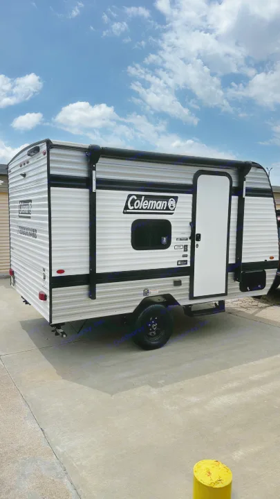Coleman travel trailer RV rental, ready for adventure. This sleek camper is parked on concrete under a blue sky, perfect for camping.. Keystone RV 13B travel Trailer 2026