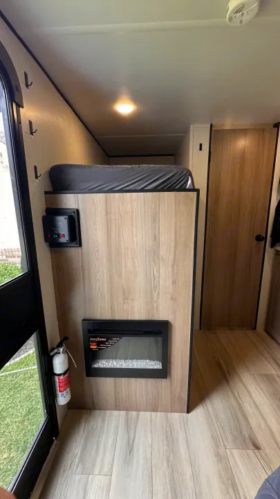 RV rental's cozy interior: bunk bed, electric fireplace, control panel, and fire extinguisher for safety.. Keystone RV 13B travel Trailer 2026