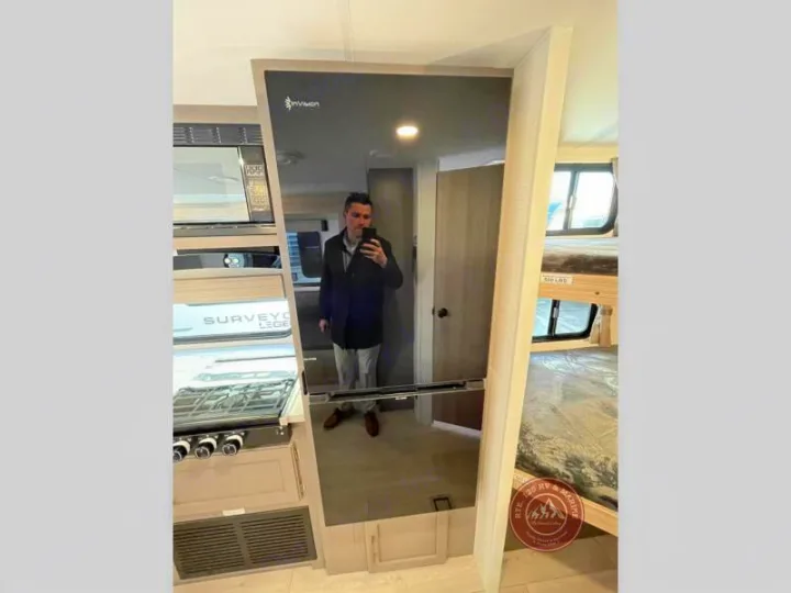 Interior of an rv rental showing kitchen appliances, a large fridge reflection, and bunk beds. Perfect for your next adventure.. KZ Sportsmen Select 2026