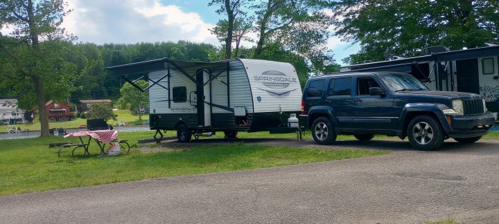 This lakeside rv rental setup features a Springdale travel trailer, towed by a Jeep, ready for a relaxing camping trip.. Keystone RV Springdale 2024