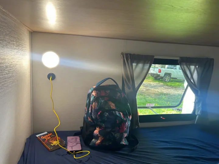 Cozy RV rental bunk bed with reading light, charging phone, and backpack, ready for adventure.. Gulf Stream Grand River 25BH 2026