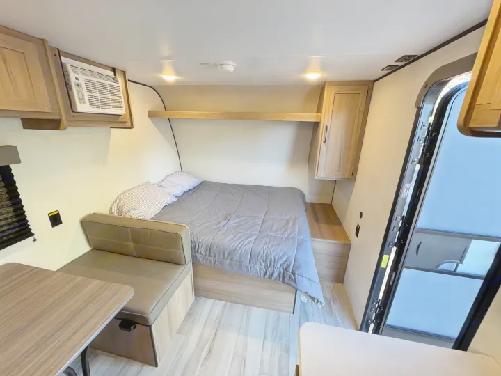 Cozy rv rental bedroom with a bed, dinette, AC unit, and light wood cabinetry. Perfect compact RV interior for travel.. Coleman Coleman 17B 2026