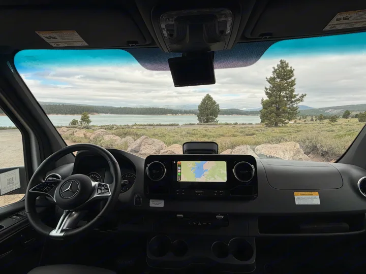 Inside an RV rental, a dashboard view with navigation to Baca Reservoir, overlooking a scenic lake and mountains.. Coachmen Prism 2026