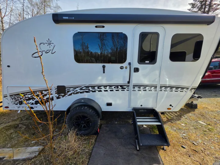 White InTech Sol RV rental: a modern travel trailer with a Thule awning, off-road tires, and distinctive tire track graphics.. InTech RV Sol 2026
