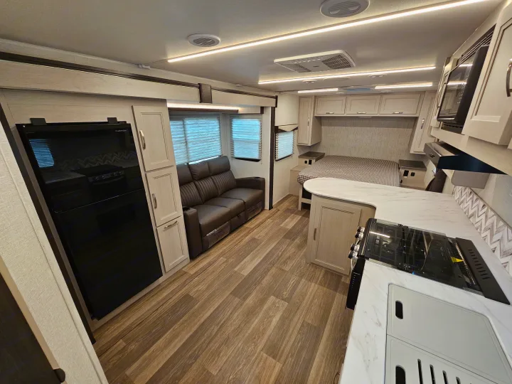 Bright, modern RV rental interior showcasing a full kitchen, comfortable sofa, and inviting bedroom setup.. Cruiser RV Shadow Cruiser 2025
