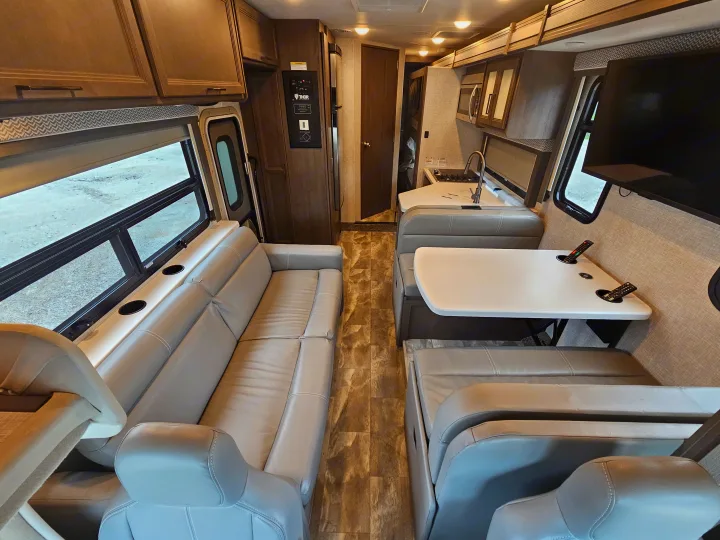 RV rental interior showcasing a spacious living area with sofa, dinette, kitchen, and overhead storage.. Thor Quantum 2023