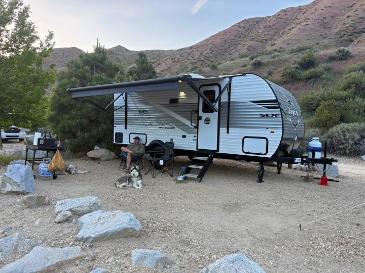 RV rental travel trailer camping: Man and husky relax outdoors in a mountain landscape.. Jayco Jay Flight SLX Baja Edition 2025