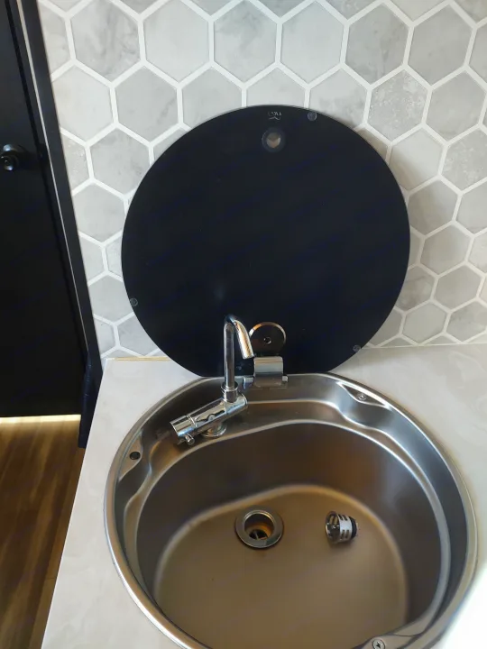 Efficient RV rental sink area: stainless basin, collapsible faucet, and black hinged cover against hex tiles.. Jayco Jay Feather Air 18mbh 2024