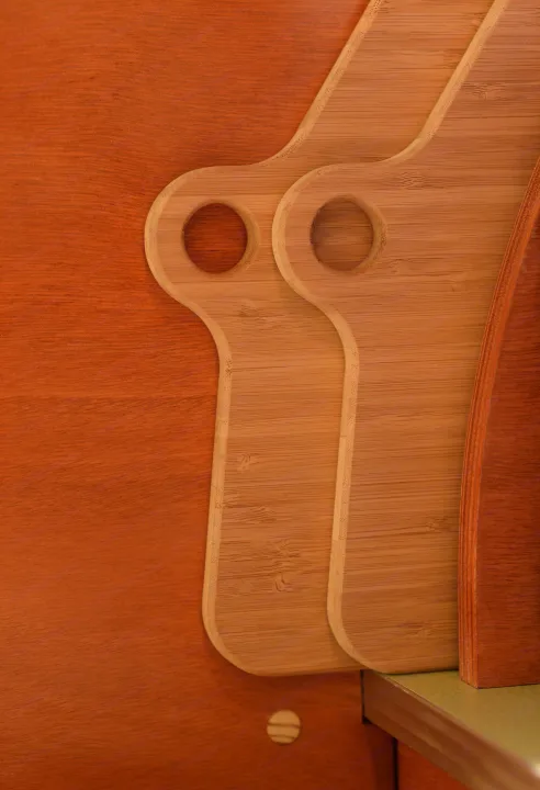 Vertical storage of light wood bamboo cutting boards against a dark orange wooden wall in an RV rental, optimizing space.. All Good Equipment Company Teardrop Trailer 2026