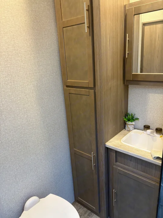 Compact RV rental bathroom featuring a sink, toilet, and ample storage cabinets for convenient travel.. Crossroads RV Volante 2021