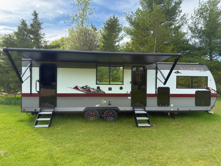 Sleek Campsite Ultra RV rental parked on green grass with awning extended. Ideal travel trailer for your next adventure.. Forest River Campsite Reserve 2025