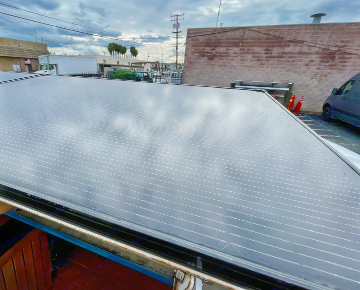 Rooftop solar panels on an RV rental, with an industrial backdrop under cloudy skies.. Ford E350 2010