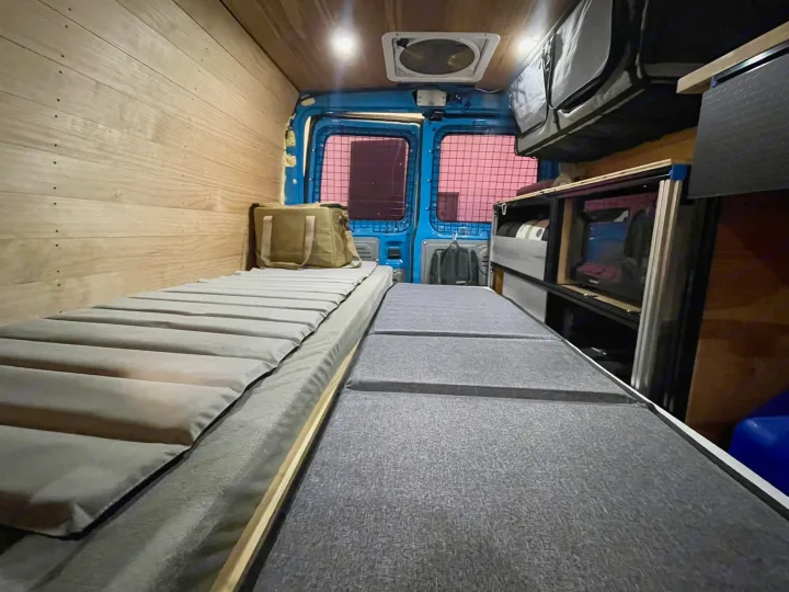 RV rental camper van interior: Two beds, wood walls, overhead storage, and rear cargo doors. Ready for your next adventure!. Ford E350 2010