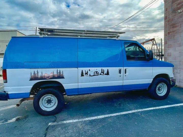 This blue & white cargo van, customized with nature decals & a roof rack, could be your next RV rental adventure vehicle.. Ford E350 2010