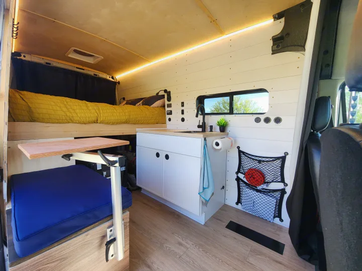 Spacious rv rental with a bright interior, raised bed, kitchenette, and flexible dining area, perfect for road trips.. Ford Transit 2022