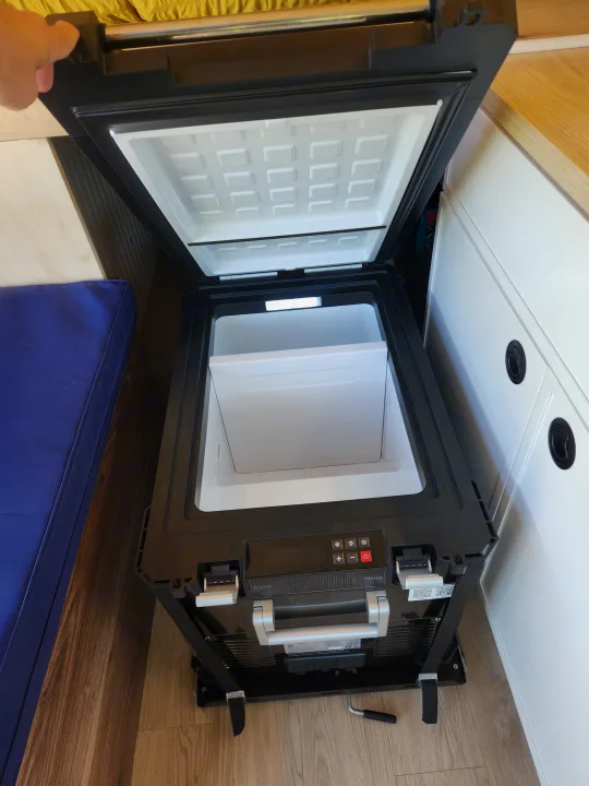 RV rental: Open portable fridge with illuminated interior, control panel, and storage basket. Hand holds the lid.. Ford Transit 2022