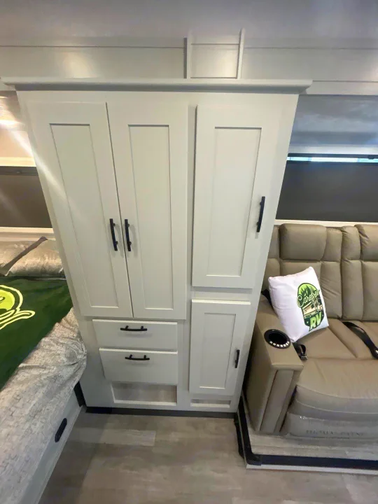 RV rental interior features: light storage cabinets, bed, & beige recliner with cupholder for comfort.. Isata 3 Series 2026