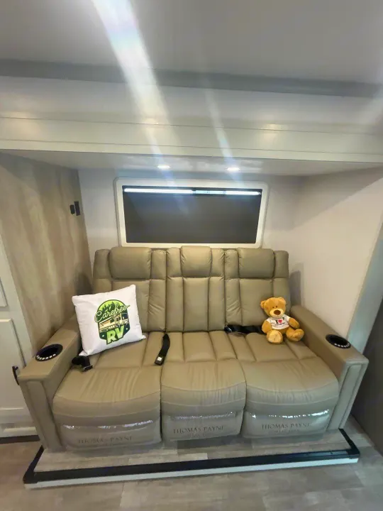 Plush tan Thomas Payne RV recliner sofa with pillows, cup holders & teddy bear, great for your rv rental.. Isata 3 Series 2026