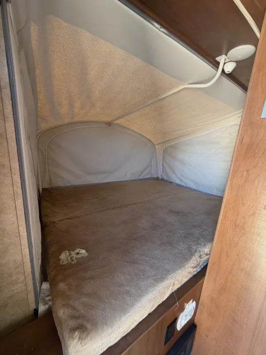 This RV rental's pop-up sleeping area features a large bed with a soft, brown Teddy Bear blanket and canvas walls.. Jayco Jay Feather 2017