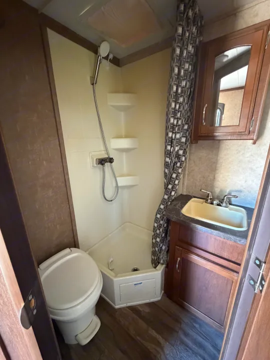 RV rental bathroom: compact space with toilet, corner shower, sink vanity, and mirrored cabinet.. Jayco Jay Feather 2017