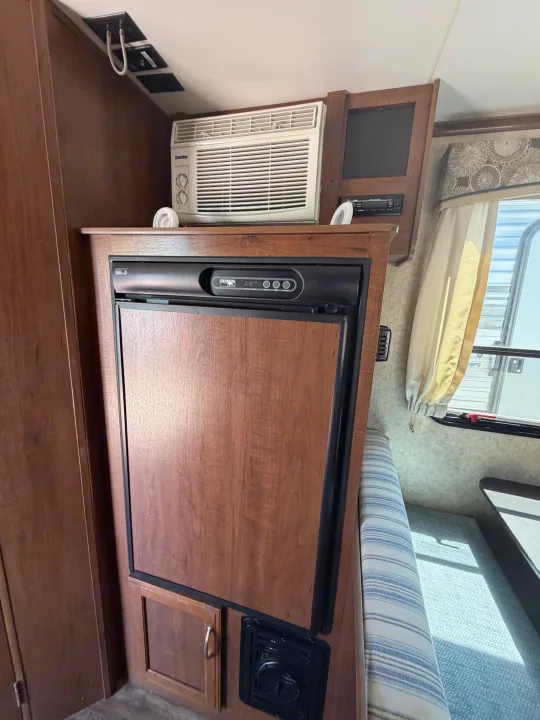 RV rental interior features a compact fridge, Danby AC unit, and comfy dinette. Ideal camper living space.. Jayco Jay Feather 2017