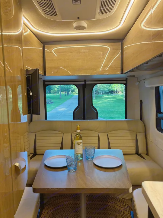 Cozy RV rental interior: A dining table set with wine and glasses, surrounded by comfy seating and LED lights.. Winnebago Era 2017