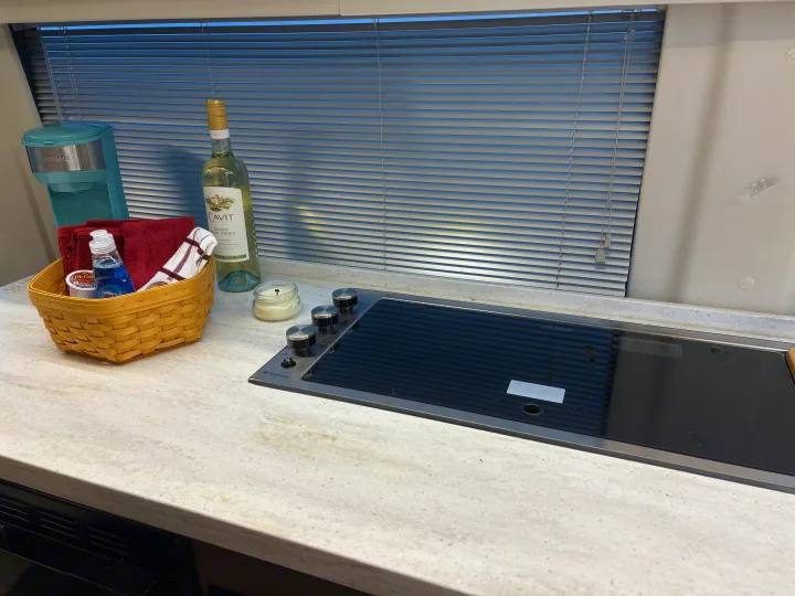 RV rental kitchen: a bright countertop with an induction cooktop, coffee maker, wine, and a basket holding towels & soap.. Winnebago Era 2017