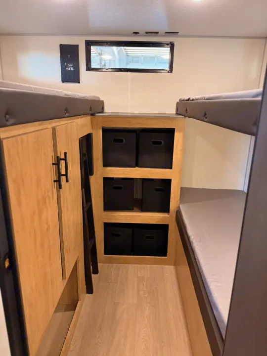 This RV rental features bunk beds, a ladder, integrated storage with black bins, and a window, optimizing space.. Forest River Campsite Reserve 2026