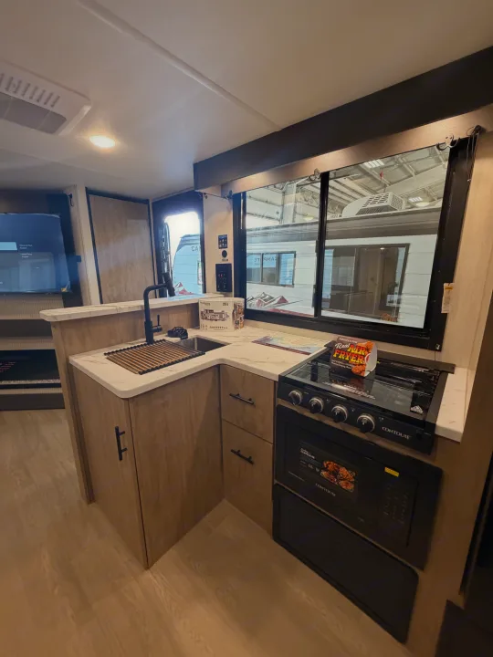 Explore this modern RV rental kitchen. Features include a sink, stove, oven, and handy air fryer for delicious meals on the go.. Forest River Campsite Reserve 2026