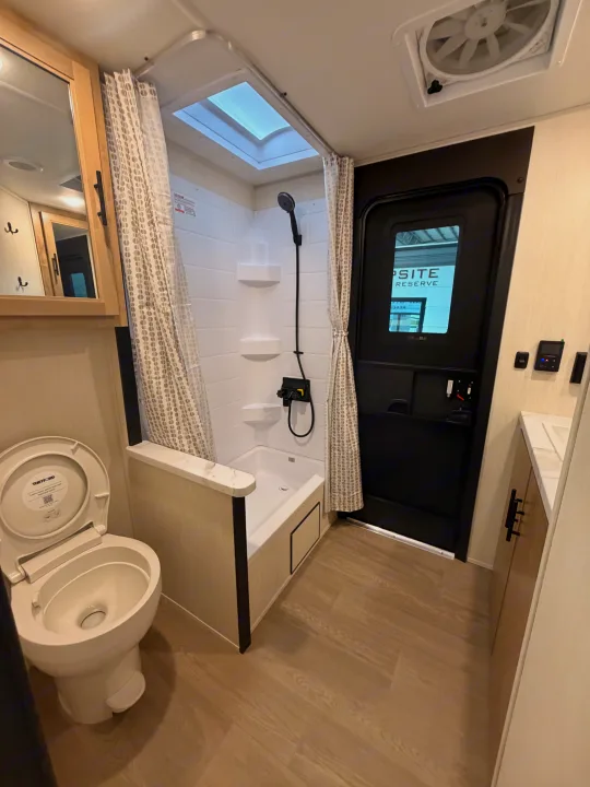This RV rental offers a well-appointed bathroom featuring a toilet, shower with a skylight, and a compact vanity.. Forest River Campsite Reserve 2026