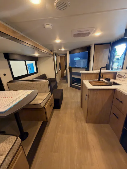 Inside a sleek RV rental: modern kitchen, comfortable dinette, and living area with a TV, perfect for travel.. Forest River Campsite Reserve 2026