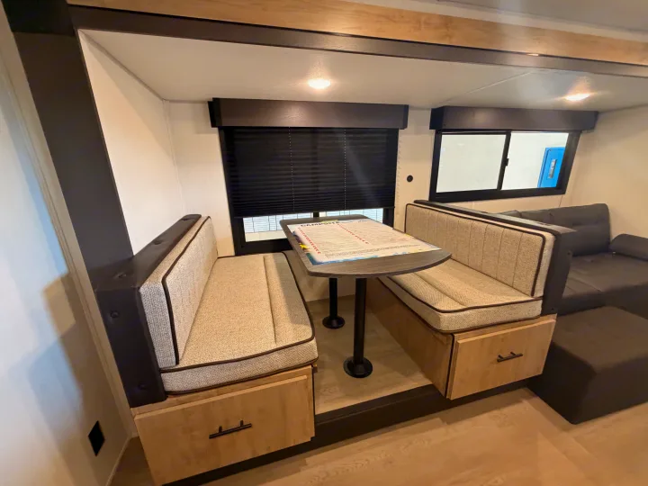 RV rental dinette: cozy booth seating with light fabric, dark trim, under-bench storage, and a central table for meals.. Forest River Campsite Reserve 2026
