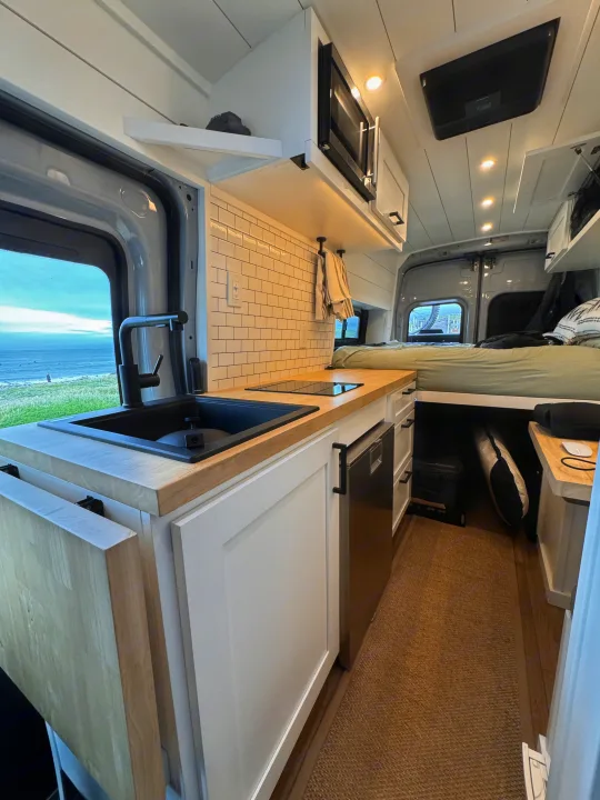 This RV rental boasts a modern kitchen, comfy bed, & ocean views. Compact, bright interior perfect for van life adventures.. ActiVan Ford Transit 350 AWD 2023