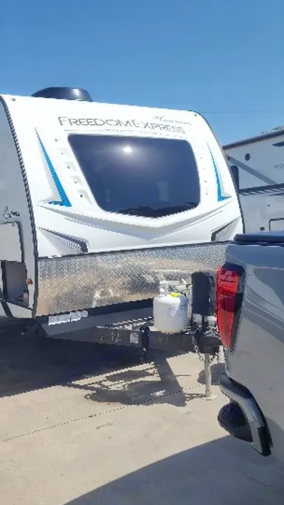 Experience an RV rental! White Freedom Express travel trailer, with a propane tank, hitched to a truck for your next road trip.. Coachmen 292bhs 2021