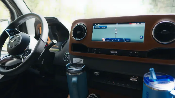 Experience a Mercedes-Benz rv rental: dashboard view with active navigation, Apple CarPlay, music, and stylish wooden trim.. Other Other 2026