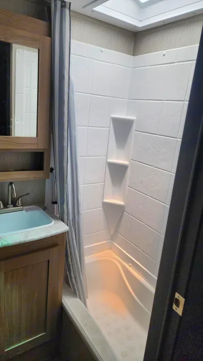 RV rental bathroom: compact shower with built-in shelves, bathtub, sink, and mirror.. Coachmen 292bhs 2021