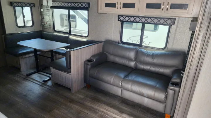 RV rental interior features a comfortable dinette, sofa with cupholders, and wood-look flooring for a cozy trip.. Coachmen 292bhs 2021