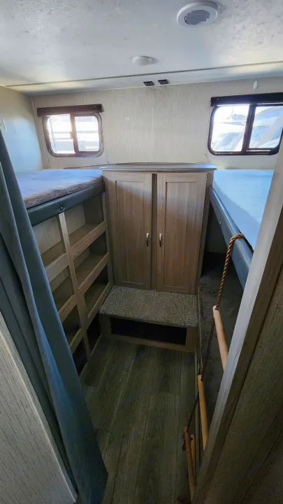 RV rental bunkhouse: two bunk beds, central storage, a ladder, and windows. Functional camper interior for family travel.. Coachmen 292bhs 2021