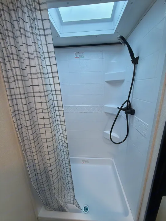 Modern RV rental shower featuring a skylight, handheld shower head, and plaid curtain.. Jayco Jay Flight SLX 175 FQW Baja 2026