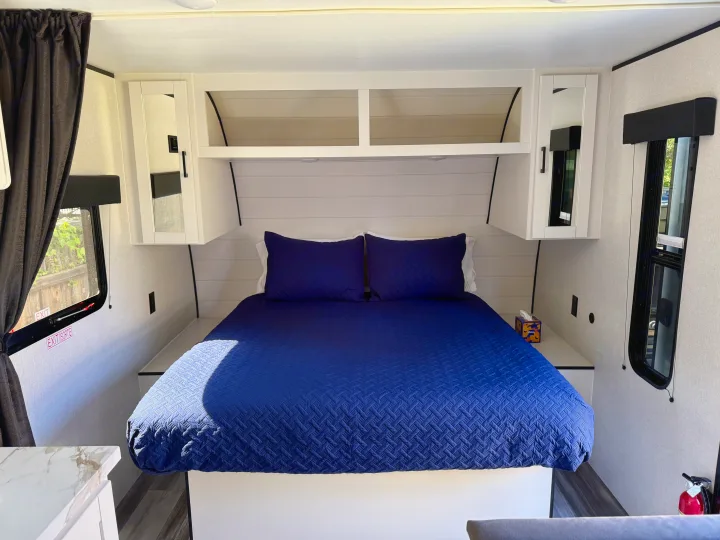 Modern RV rental bedroom: blue quilted bed, shiplap, mirrored cabinets, storage, and windows.. Jayco Jay Flight SLX 175 FQW Baja 2026