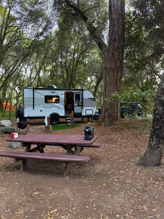 Jayco travel trailer RV rental at a wooded campsite with a picnic table, perfect for camping.. Jayco Jay Flight SLX 175 FQW Baja 2026