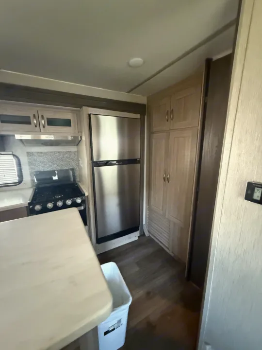 RV rental kitchen featuring a stainless steel fridge, stove, light wood cabinetry, a counter, and wood-look flooring.. Coachmen Other 2021