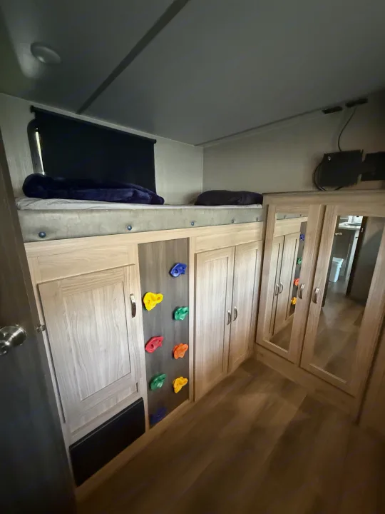 Cozy RV rental bunk bed area with integrated storage, colorful rock climbing holds, and mirrored closets for family adventures.. Coachmen Other 2021