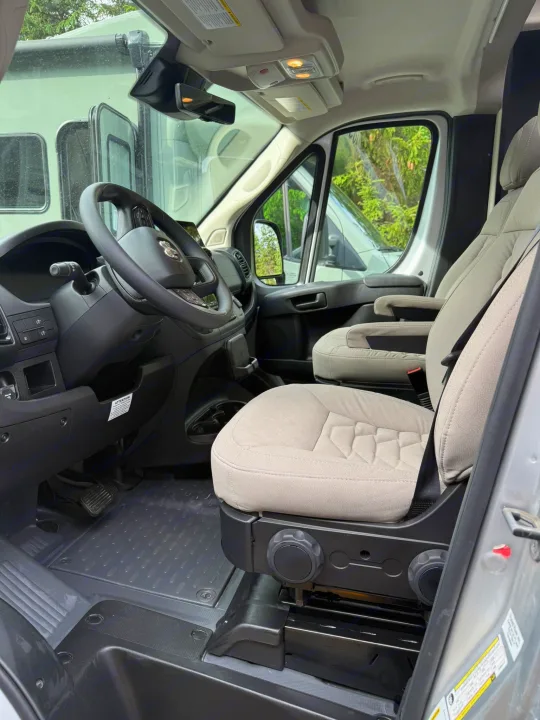 **RV rental** driver's cabin: Steering wheel, dashboard, and light beige seats ready for the road.. Coachmen Nova 2024