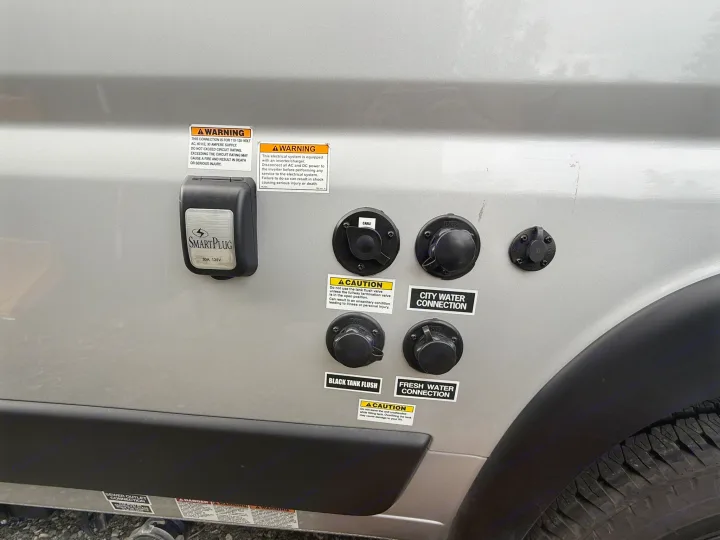 RV rental utility panel: power (30A), cable, city & fresh water, and black tank flush connections on the side.. Coachmen Nova 2024