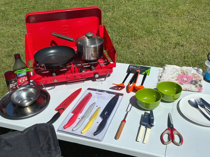 RV rental camp kitchen setup: portable stove, cookware, knives, and dining accessories ready for outdoor cooking.. Dodge Grand Caravan 2005