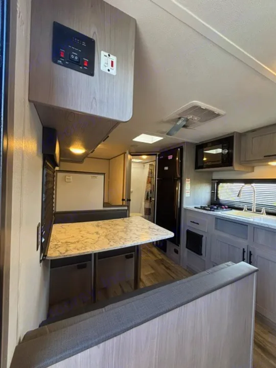 Modern RV rental interior with a bright kitchen, full-size fridge, microwave, and a cozy dinette, perfect for travel comfort.. Dutchmen Coleman Lantern LT 2024